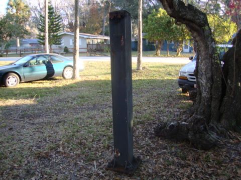 1986 Ford Bronco - A black metal post stands in a yard between a teal coupe and a white truck.