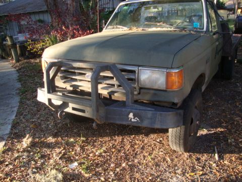 1986 Ford Bronco - Green Ford F-Series truck with a brush guard and flatbed is parked outdoors.