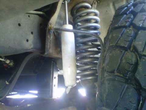 1994 Ford F-150 - Close-up view of the suspension system of a truck, showing the shock absorber and coil spring.