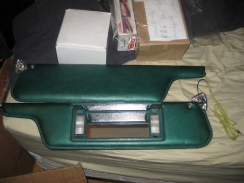 1979 Ford F-150 - Two green sun visors, one with an illuminated vanity mirror, are displayed on a bedspread with boxes in the background.