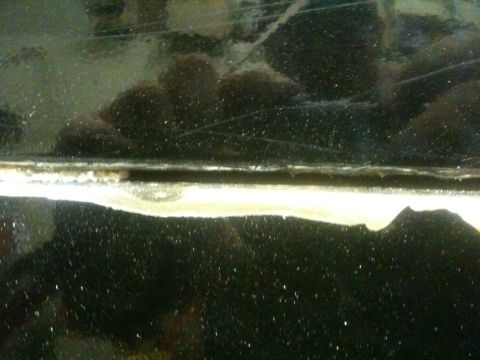 1993 Ford Bronco - Close-up of a damaged tailgate seam on a dark vehicle, showing rust and wear.