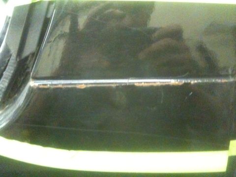 1993 Ford Bronco - Masking tape is applied to the edge of a car door, revealing minor rust damage.