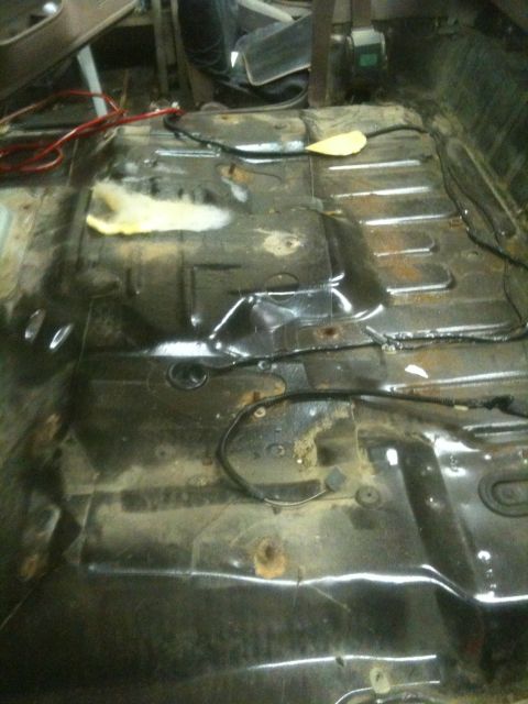 1993 Ford Bronco - The interior floor pan of a vehicle shows exposed wiring and signs of rust, suggesting a need for restoration.