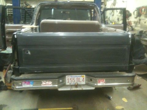 1993 Ford Bronco - The rear of a Ford Bronco is shown, with its tailgate open and a bench seat visible inside the cargo area.