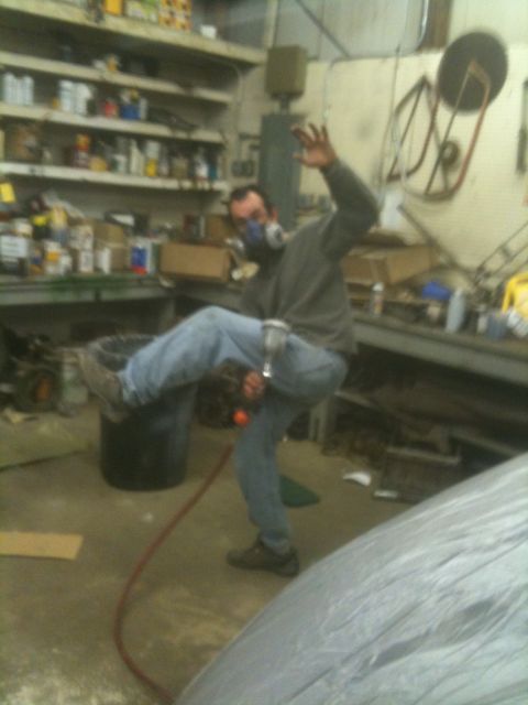 1993 Ford Bronco - A man wearing a respirator and jeans kicks a trash can in a cluttered workshop.