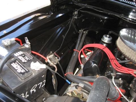 1966 Ford F-100 - Close-up view of a clean engine bay, a battery and red spark plug wires.