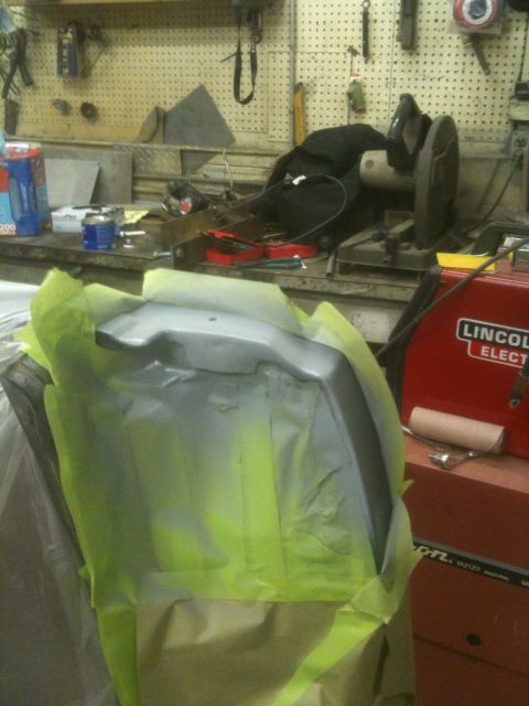 1993 Ford Bronco - A car part is prepped for painting in a workshop, with a welder visible in the background.