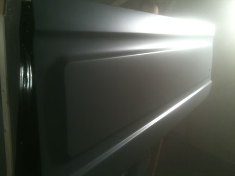 1993 Ford Bronco - A gray tailgate with distinct horizontal body lines and a chrome trim strip is shown.