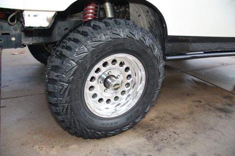 1987 Ford Bronco - This image shows a close-up of a Goodyear MT/R Kevlar tire mounted on a polished aluminum wheel, with suspension components visible.