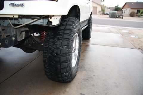 1987 Ford Bronco - Large off-road tires and suspension components are visible on a lifted truck.