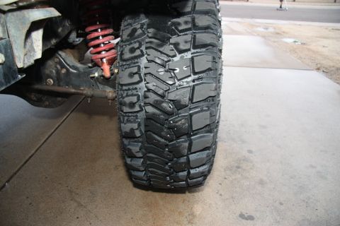 1987 Ford Bronco - A close-up view shows a off-road tire and suspension components of a vehicle.