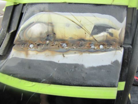 1993 Ford Bronco - Close-up of a metal panel undergoing repair, showing fresh welds and protective tape.