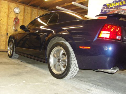 2007 Ford Mustang - The rear passenger side of a dark blue Ford Mustang is shown in a garage setting.