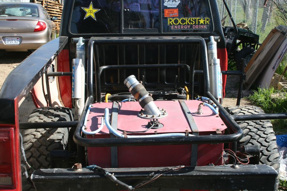 Rear view of pickup truck with custom fuel tank and roll cage. Rockstar Energy Drink sticker on window