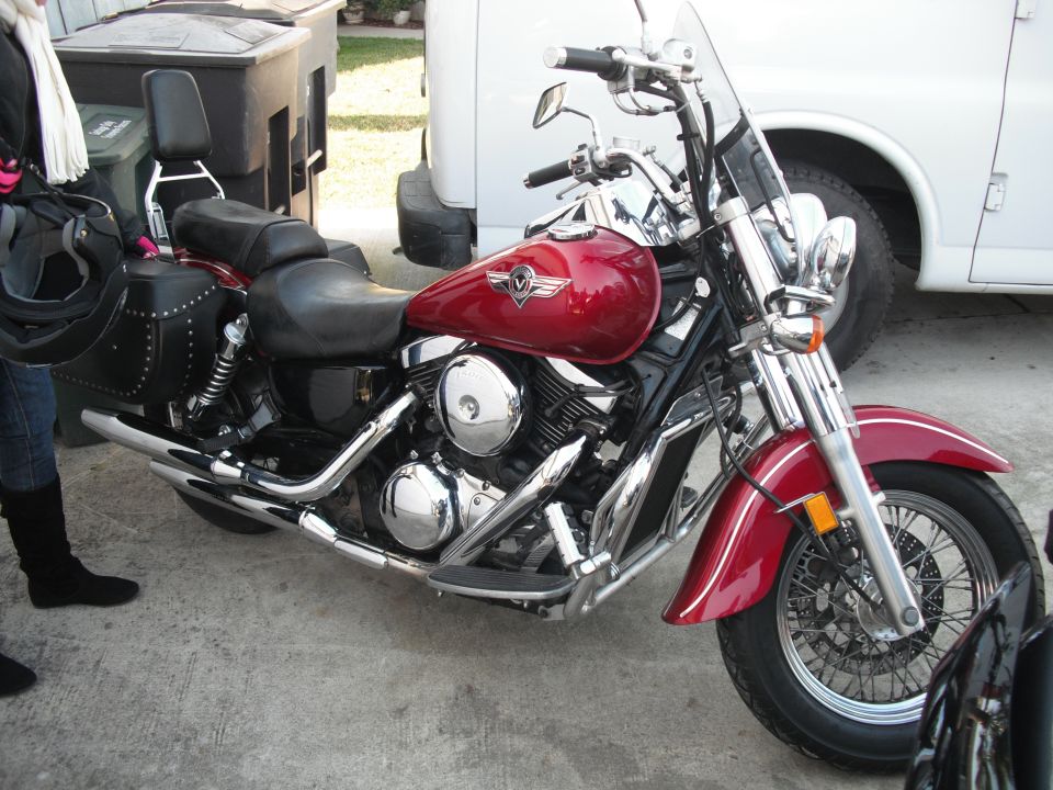 Red cruiser motorcycle parked on concrete, with a white van behind it