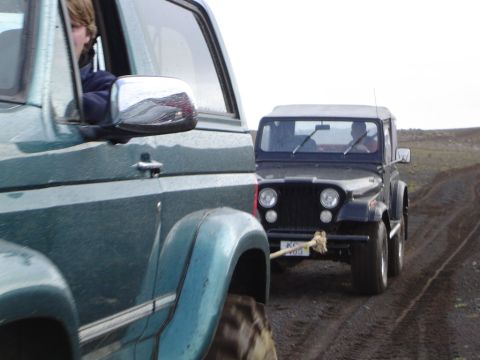 1996 Ford Bronco - Two vehicles travel on a muddy track, with one in the foreground and another following behind it.