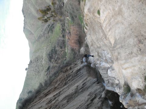 1991 Ford Bronco - A person is perched on the edge of a steep cliff, with a valley and hills in the background.