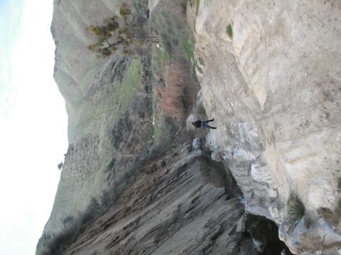 1991 Ford Bronco - A person rappels down a steep cliff face, with a winding path visible on the distant hillside.