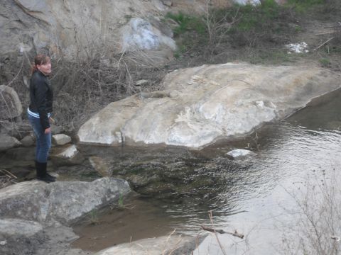1991 Ford Bronco - A woman stands on rocks beside a stream in a natural, rocky environment.