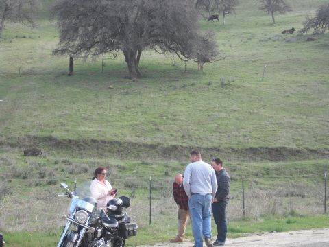 1991 Ford Bronco - A motorcycle is parked on the side of a road while a group of people converse.