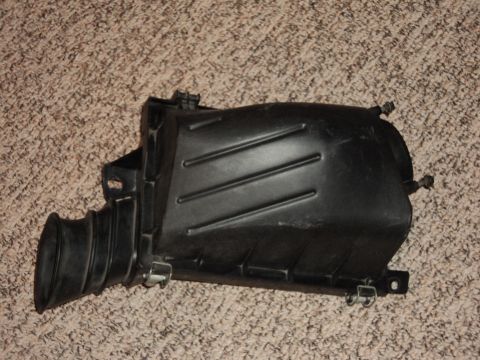 2004 Mercury Grand Marquis - This is a black plastic air intake box with a ribbed texture and a rubber hose attachment, likely for a vehicle's engine.