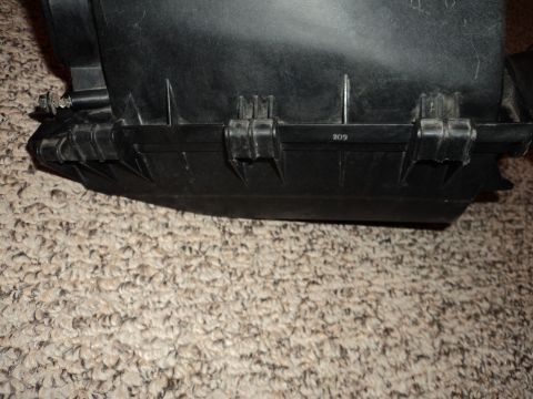 2004 Mercury Grand Marquis - Close-up of a black plastic air intake box, possibly from a vehicle, showing its construction and a stamped number.