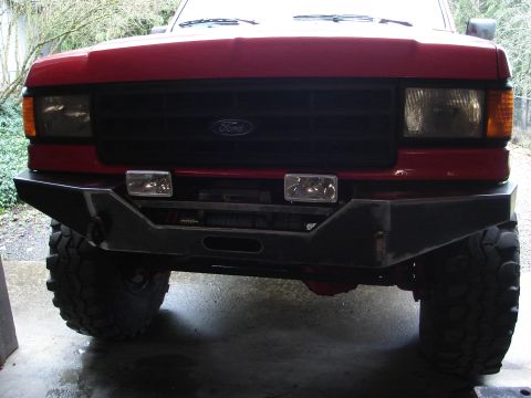 1989 Ford Bronco - This truck features a custom aftermarket bumper with a winch, and a black grille with the Ford emblem.