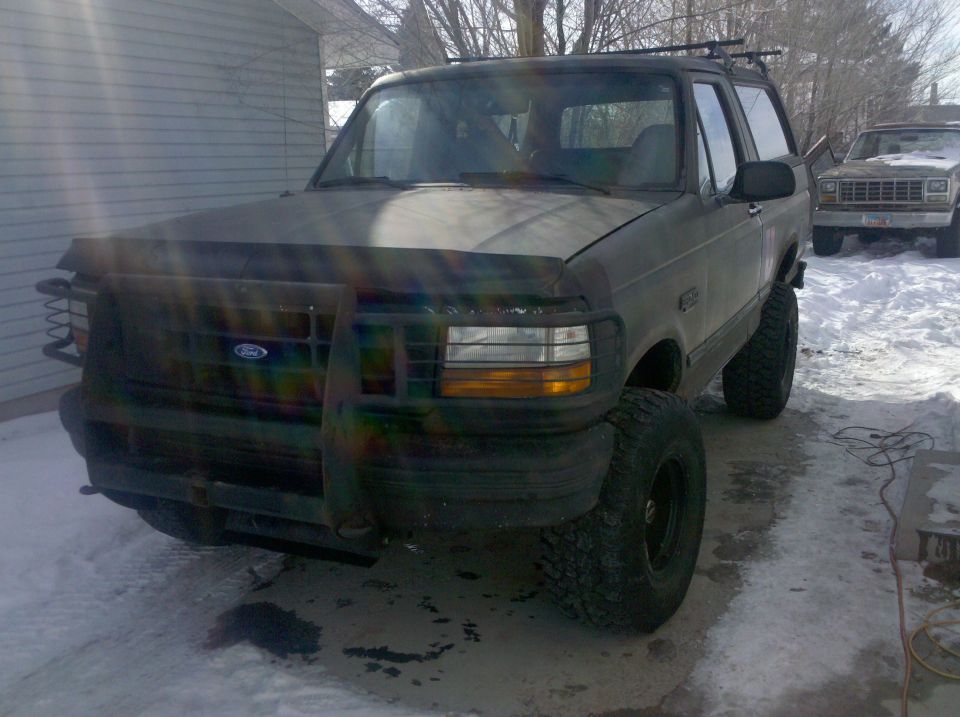 Dark green 1995 Ford Bronco with brush guard and large tires in snow