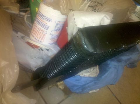 1995 Ford Bronco - A black ribbed hose lies next to various plastic containers and a blue cloth on a floor.