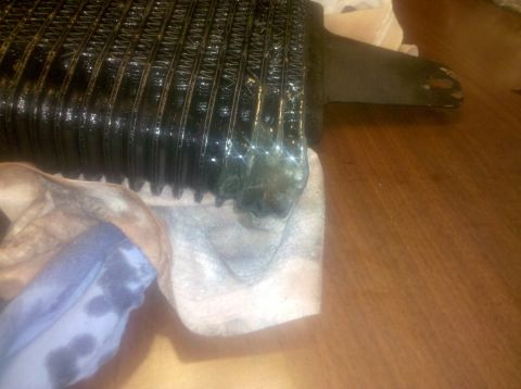 1995 Ford Bronco - A close-up view of a black oil cooler with visible fins and some green residue.