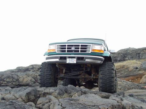 1996 Ford Bronco - This lifted Ford truck is parked on a rocky landscape with a clear sky overhead.