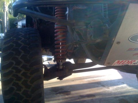 1992 Ford Ranger - Close-up view of the suspension system on a modified off-road vehicle, showing a large tire and a red shock absorber.