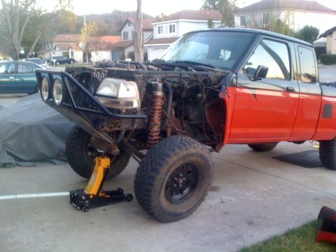 1992 Ford Ranger - This modified pickup truck, possibly a Ford Ranger, is undergoing repairs or customization with its front end disassembled and large off-ro…
