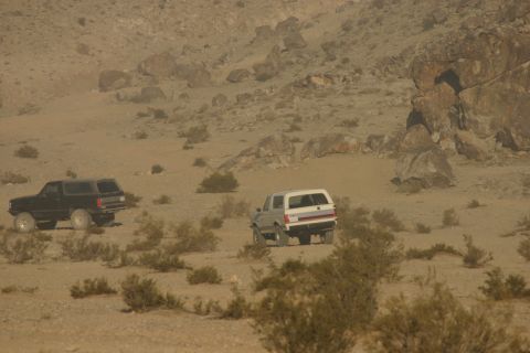 1992 Jeep Wrangler - Two SUVs traverse a dry, arid landscape under a hazy sky.