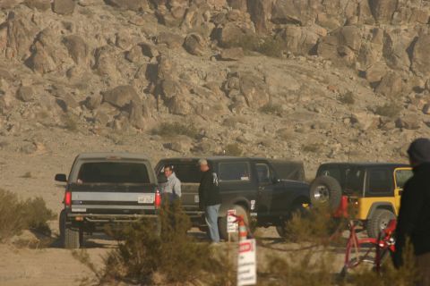 1992 Jeep Wrangler - Multiple off-road vehicles are parked in a desert environment with rocky hills.
