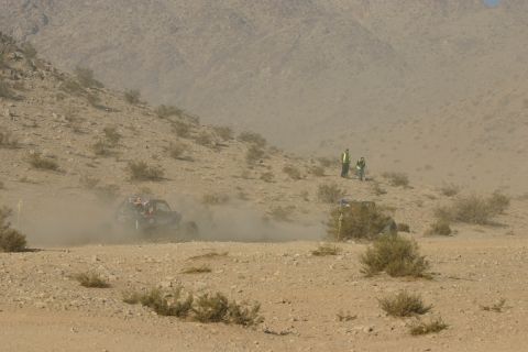 1992 Jeep Wrangler - A buggy races through a dusty desert landscape with spectators watching from a hillside.