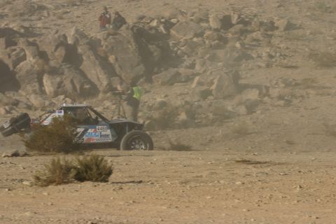 1992 Jeep Wrangler - A buggy races through a rocky, dusty terrain with spectators watching from a hillside.