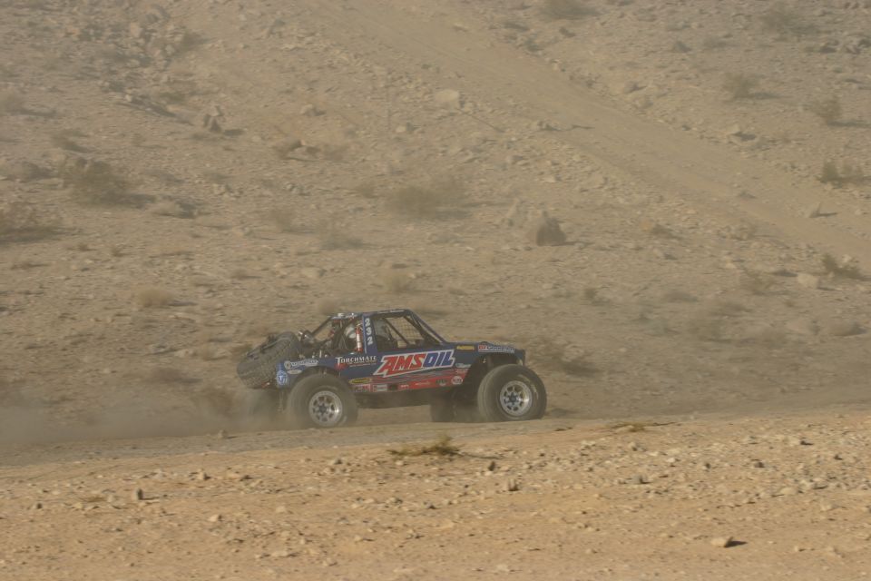 Off-road buggy with Amsoil sponsorship kicking up dust on a dirt track