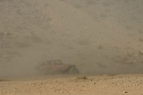 1992 Jeep Wrangler - A red off-road vehicle navigates a dusty desert terrain during a race.