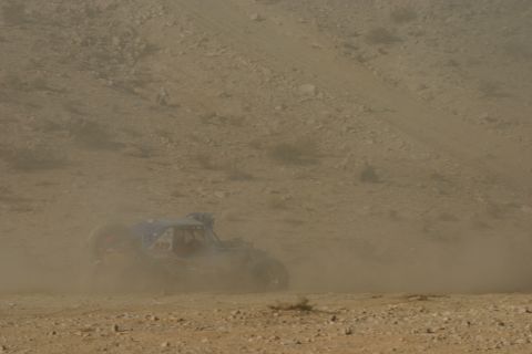 1992 Jeep Wrangler - A buggy races across a dry, dusty terrain, kicking up a large cloud of dirt.
