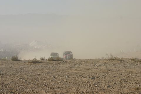 1992 Jeep Wrangler - Two off-road vehicles kick up dust during a race event in a desert landscape.