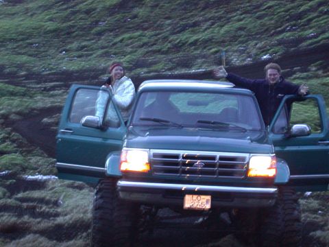 1996 Ford Bronco - Two people pose with a green Ford Bronco in a grassy, hilly landscape.