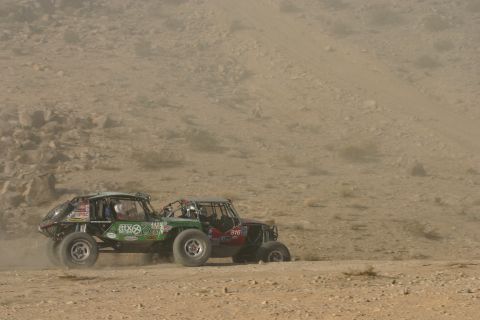 1992 Jeep Wrangler - Two off-road vehicles compete in a desert race, kicking up dust as they navigate the terrain.