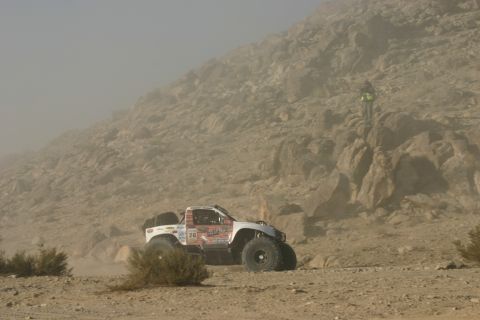1992 Jeep Wrangler - A modified off-road truck navigates a dusty, rocky landscape during a race.
