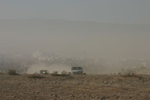 1992 Jeep Wrangler - Off-road vehicles traverse a dusty landscape near a large gathering of people and tents.
