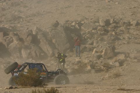 1992 Jeep Wrangler - Off-road buggy competes in a desert race, with spectators watching from rocky terrain.