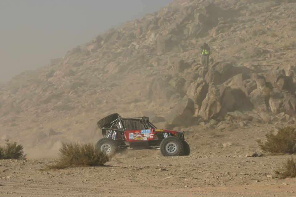 Red off-road buggy kicking up dust on a desert course