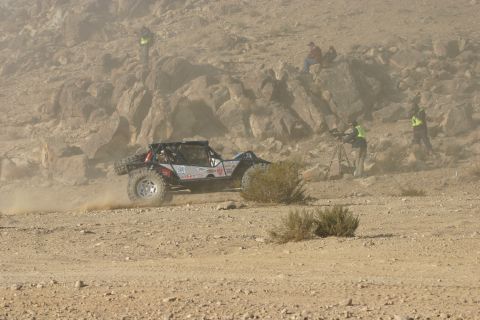 1992 Jeep Wrangler - An off-road buggy kicks up dust as it navigates a rocky, desert landscape during a race.