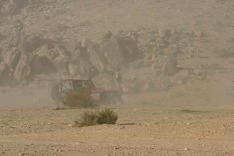 1992 Jeep Wrangler - A red off-road buggy races through a dusty desert landscape, with spectators visible on a rocky hillside.