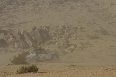 1992 Jeep Wrangler - A buggy races through a dusty desert landscape, with spectators on a rocky incline.